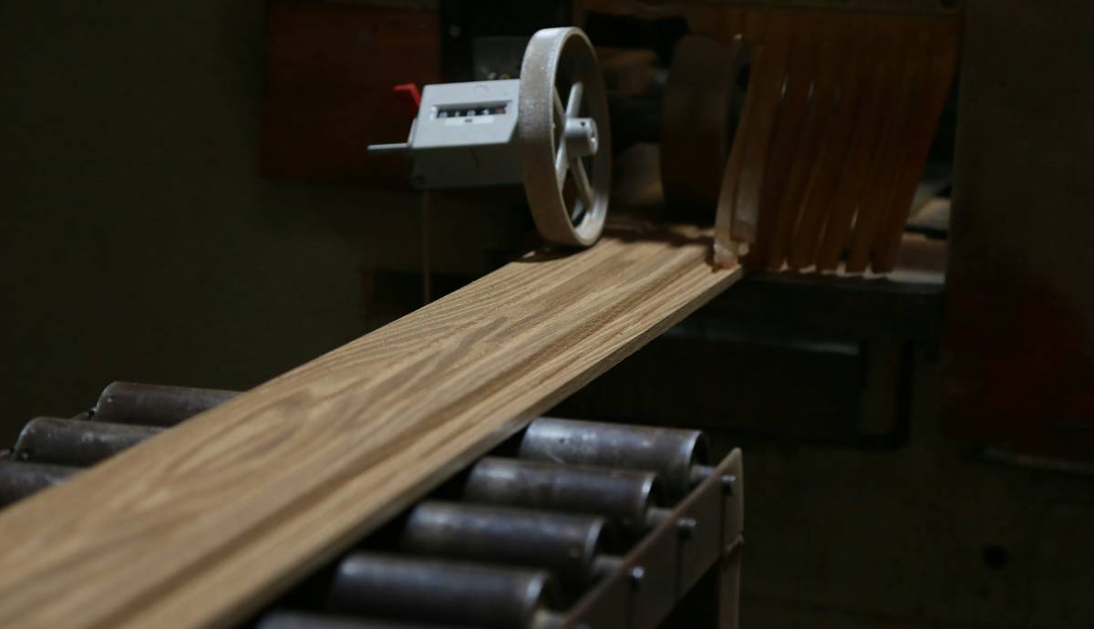 how to build a belt sander showing a completed DIY unit mounted on a bench with labeled parts: motor, drive pulley, idler pulley, and aluminum platen
